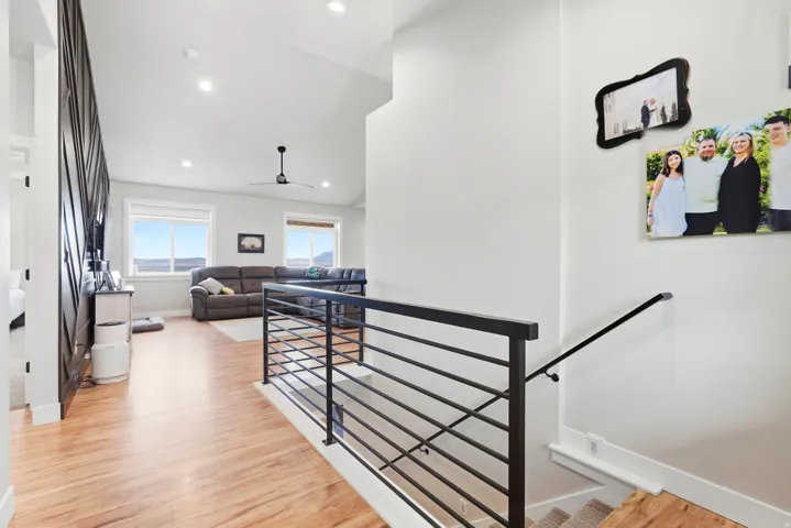 Vaulted ceilings, recessed lighting, wood-finish flooring, metal bar railing, and ceiling fan