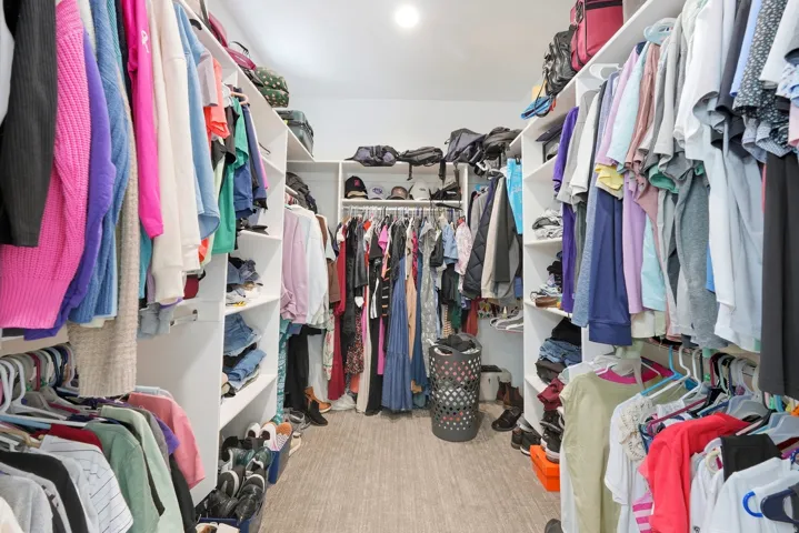 Customized closet system featuring multiple hanging rods, integrated shelving, and wood-finish flooring