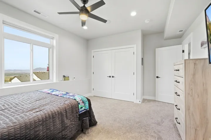Recessed ceiling lighting, a modern ceiling fan, large windows, and neutral carpeting