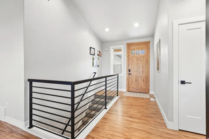 Wood-finish flooring, recessed lighting, and a modern horizontal metal railing