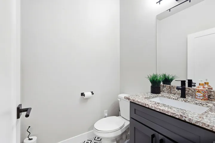 Black vanity with a stone countertop, under-mount sink, and matte black faucet