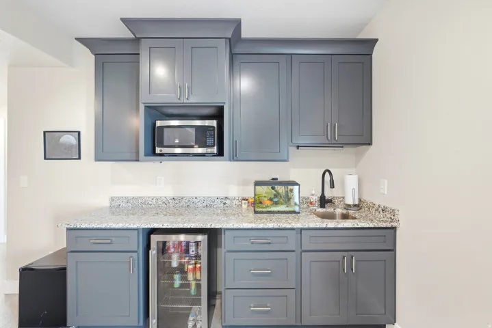 Built-in cabinetry with a stone-finish countertop, undermount sink, and beverage refrigerator