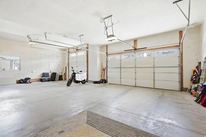 Spacious garage featuring a concrete floor, two overhead garage doors with windows, and exposed wooden framing