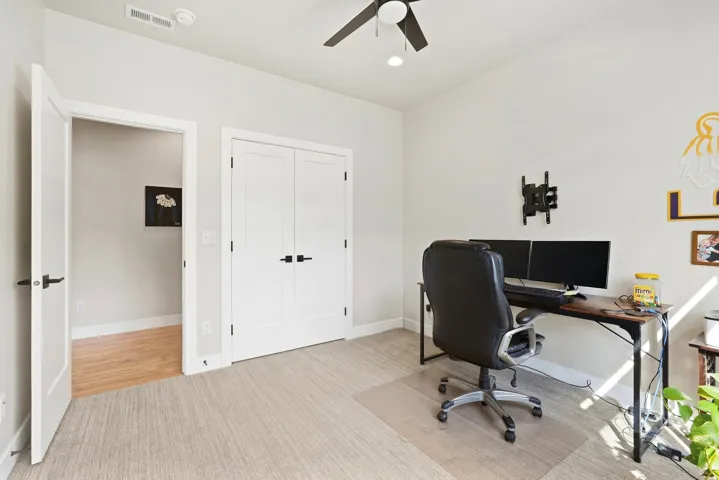 Neutral-toned carpeting, white walls, and a ceiling fan with integrated lighting