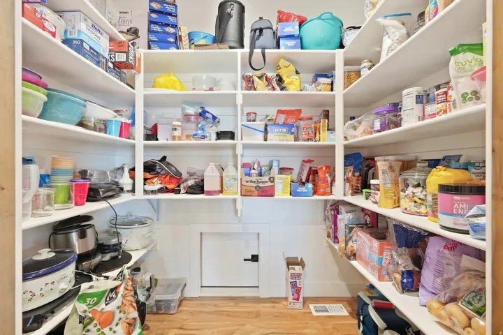 Walk-in pantry featuring extensive built-in shelving, white shiplap walls, and wood-finish flooring