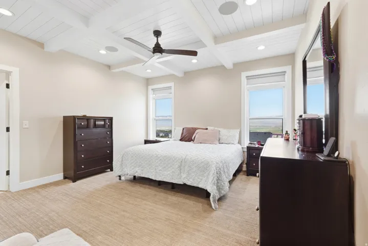 Tray ceiling with white wood paneling and exposed beams