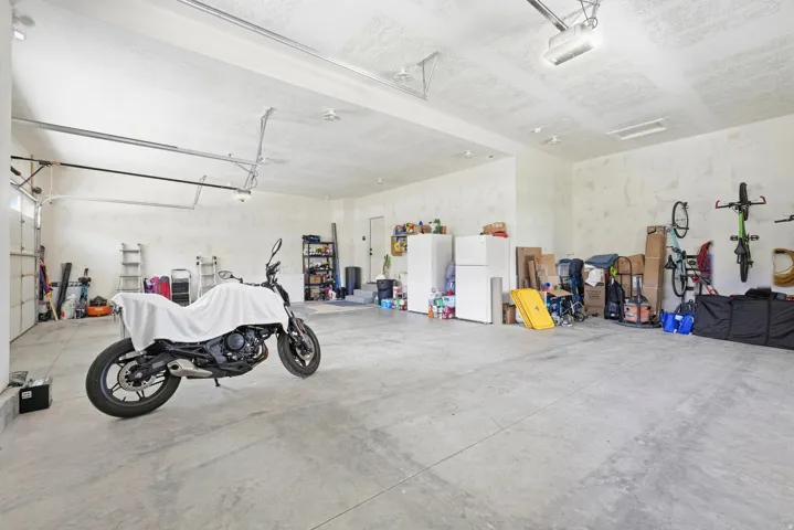 Spacious garage with concrete flooring, overhead lighting, and white walls