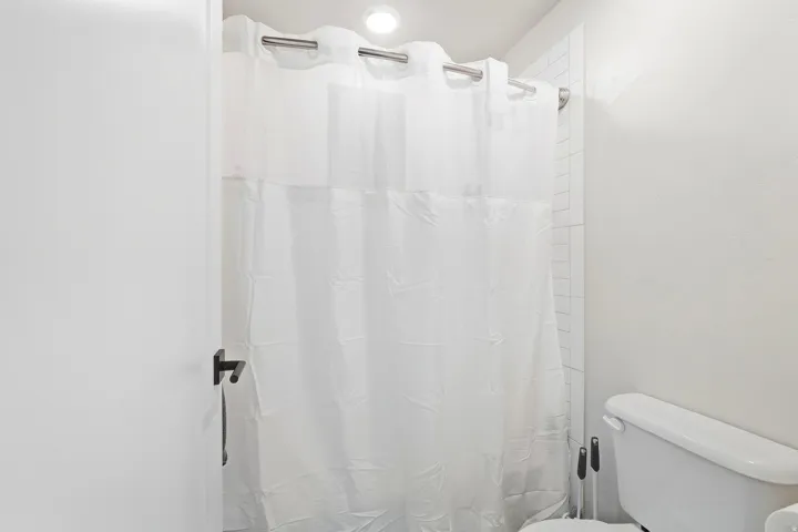 Recessed ceiling lighting illuminates the vertical subway tile shower surround