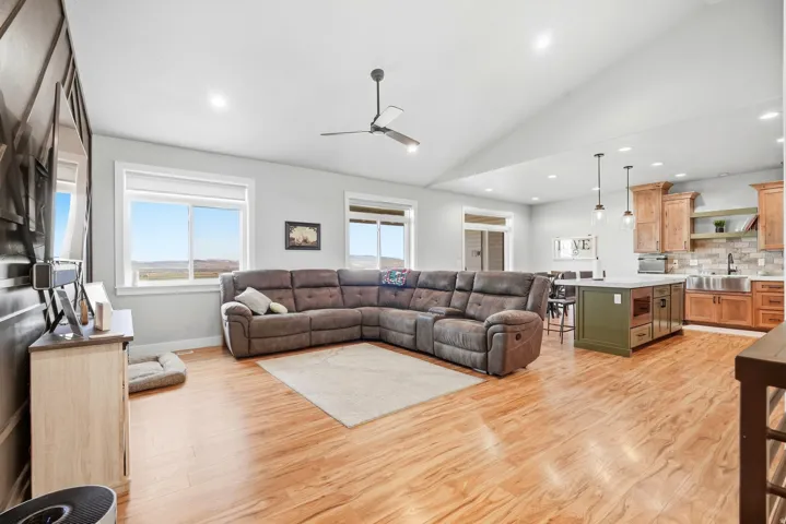 Vaulted ceiling, recessed lighting, wood-finish flooring, kitchen island with seating, pendant lighting