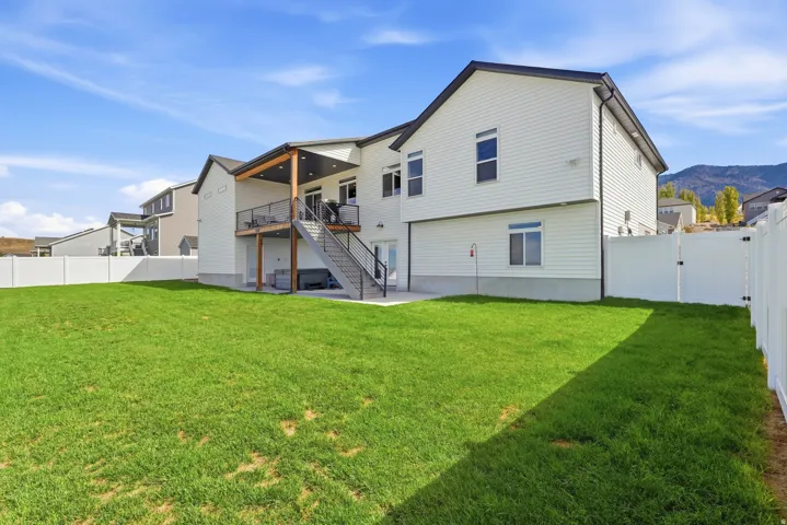 Expansive lawn space, full perimeter privacy fencing, covered upper-level deck, lower-level patio, and exterior staircase