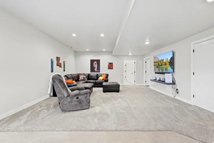 Spacious room with light gray carpeting, neutral wall color, recessed lighting, and white doors with matte black hardware