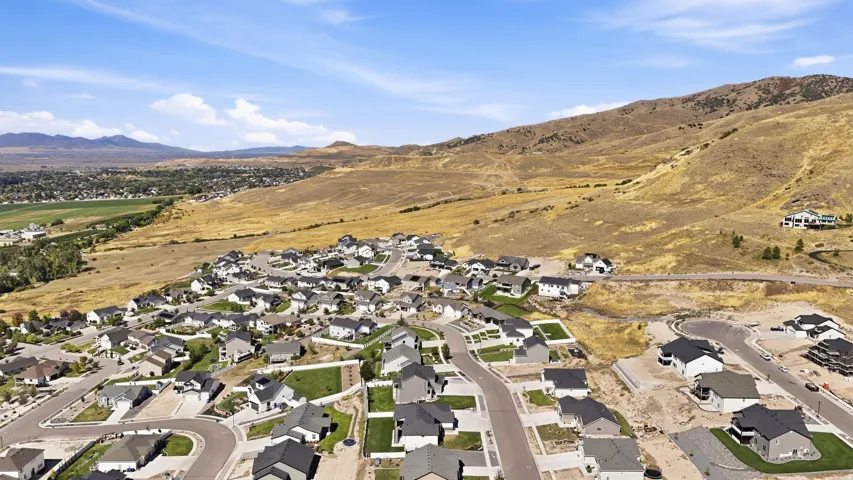 Expansive development featuring a collection of modern residences with diverse architectural styles, surrounded by natural terrain and open land