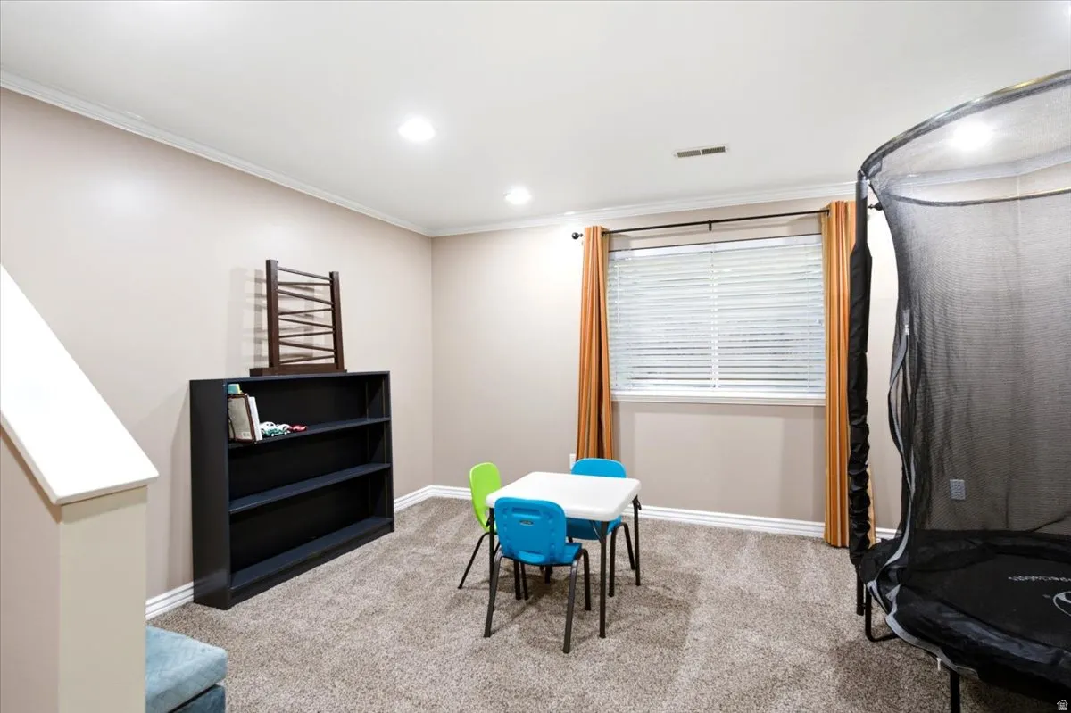 Recessed lighting, crown molding, and neutral wall tones complement the window with blinds