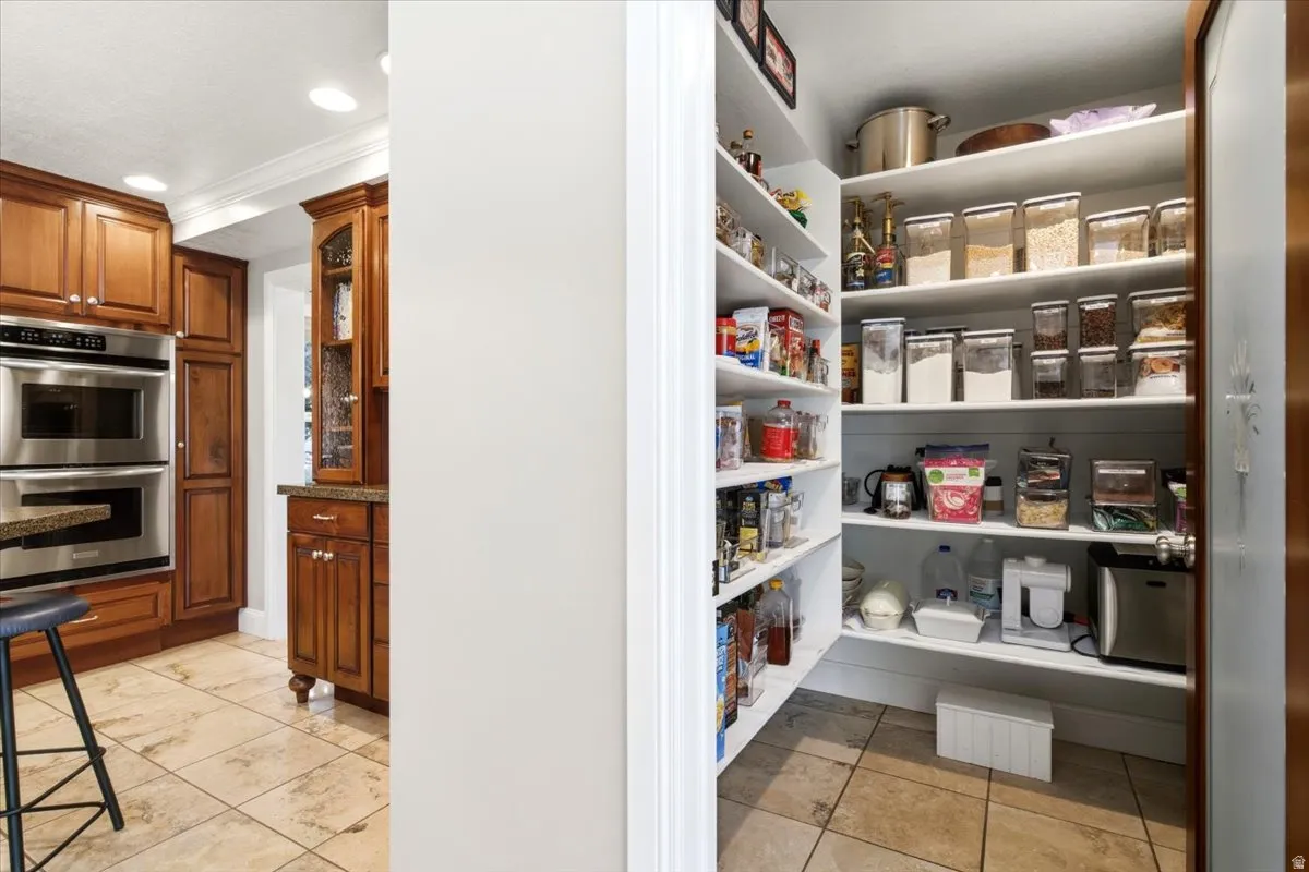 Kitchen featuring wood cabinetry, stainless steel double ovens, and stone-finish tile flooring