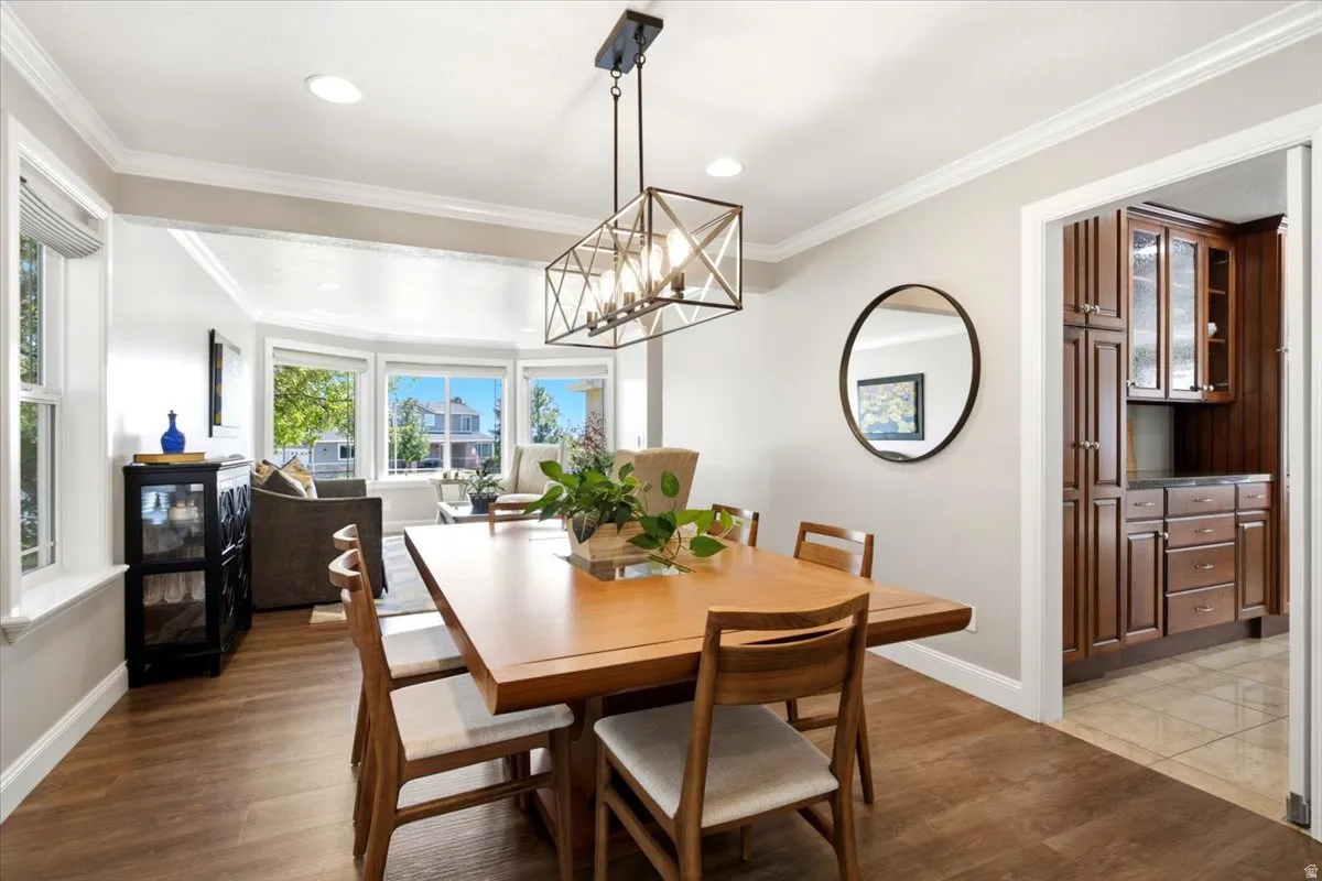 Dining area featuring wood-finish flooring, a contemporary linear chandelier, and a pass-through to a room with built-in cabinetry and a countertop