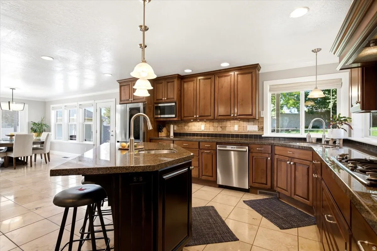Kitchen featuring wood cabinetry, stainless steel appliances, granite countertops, and tile flooring