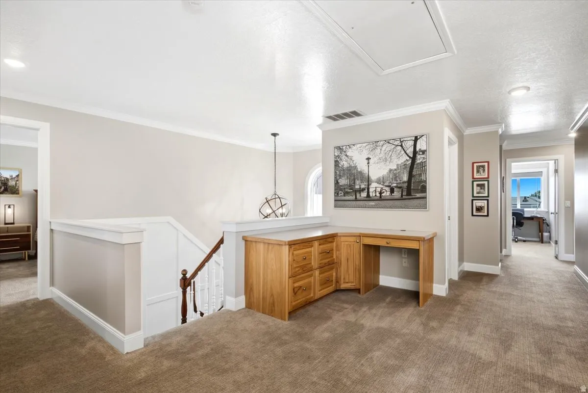 Built-in desk cabinetry with wood finish, plush carpeting, recessed lighting, and crown molding