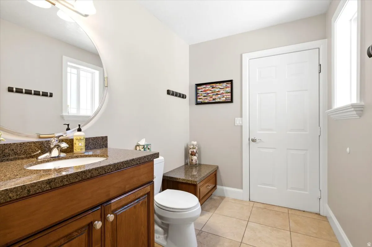 Bathroom featuring a wood-finish vanity with a built-in sink, granite countertop, and polished chrome faucet
