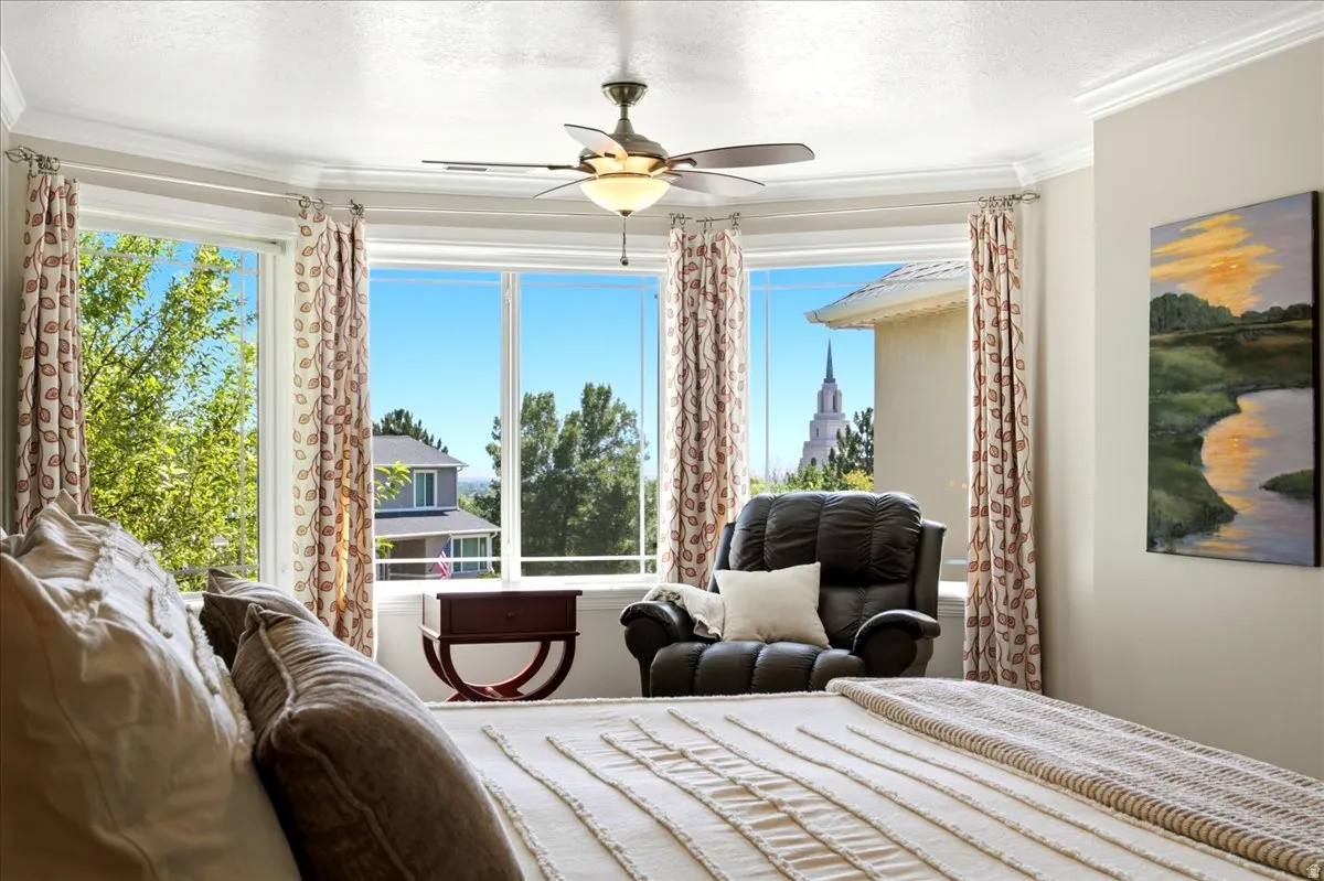 Bay window featuring multiple large windows, crown molding, and a ceiling fan
