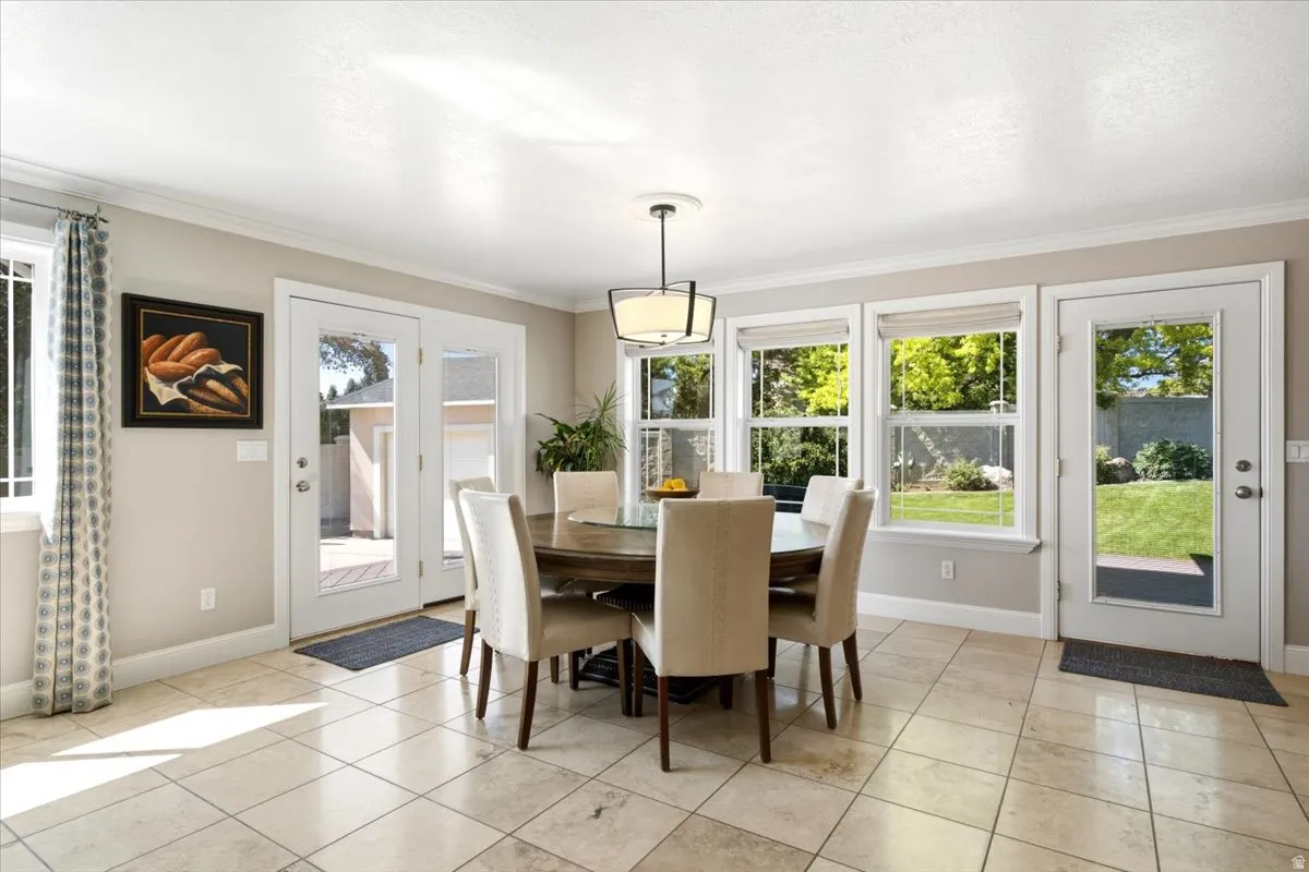 Dining area with tile flooring, crown molding, and multiple windows