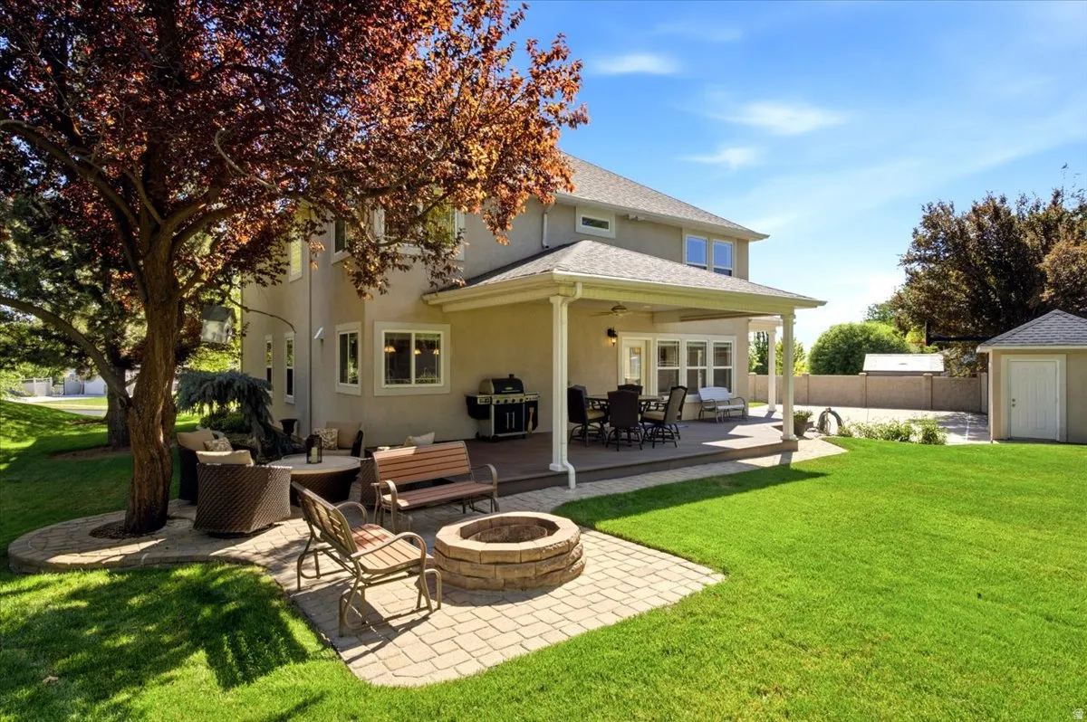 Expansive backyard featuring a covered patio, paved fire pit area, and detached shed