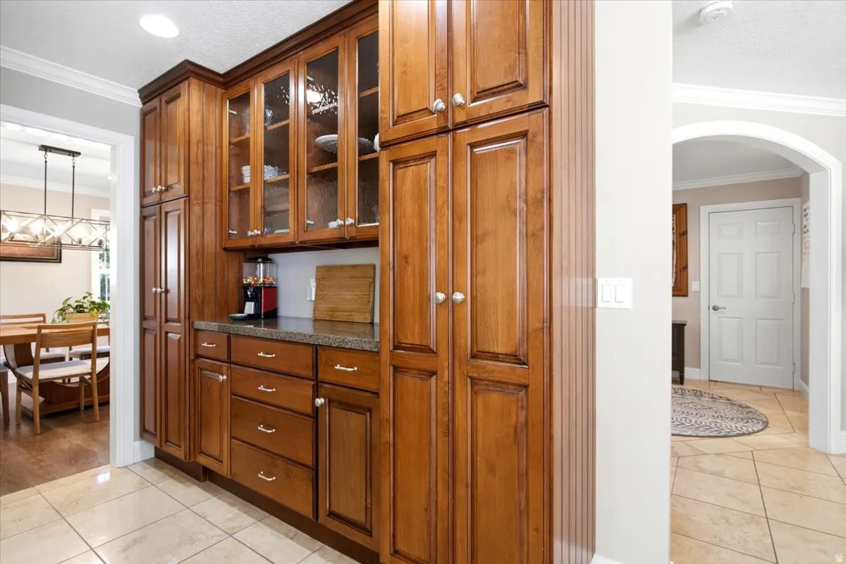 Wood-finish cabinetry with glass-front uppers, solid surface countertops, and tile flooring