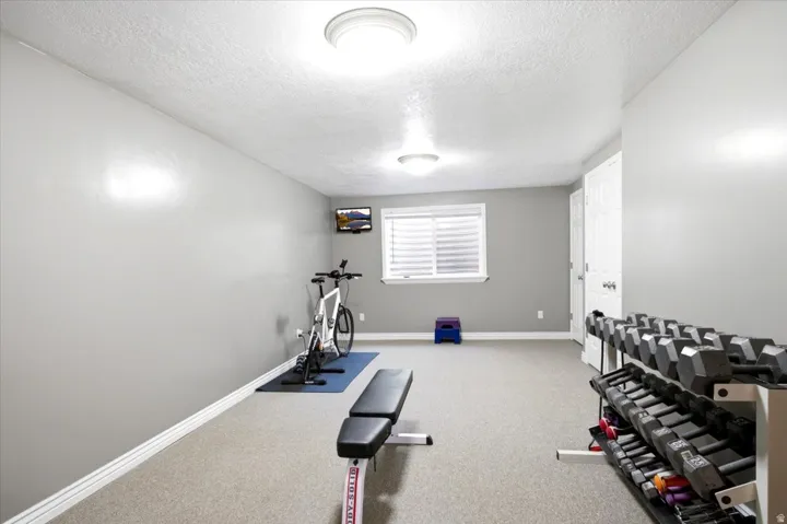 Carpeted room with a single window featuring horizontal blinds, recessed lighting, and a white interior door with a silver-toned handle