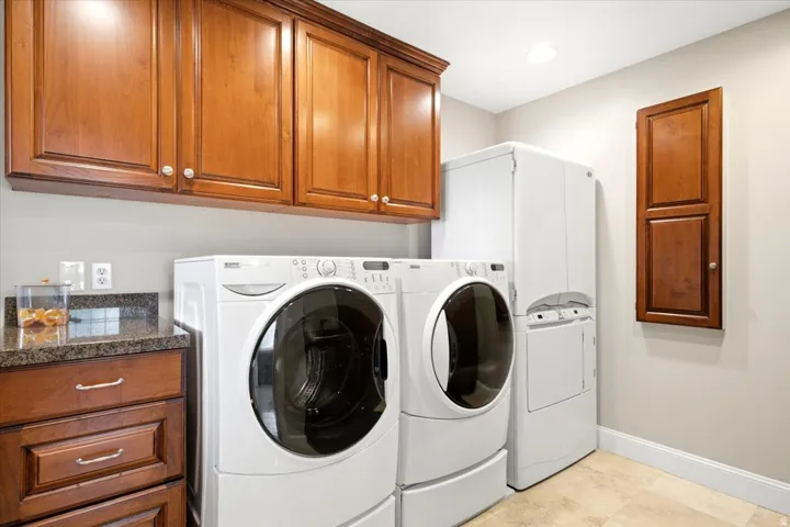 Laundry area featuring wood cabinetry, granite-finish countertop, and tile flooring