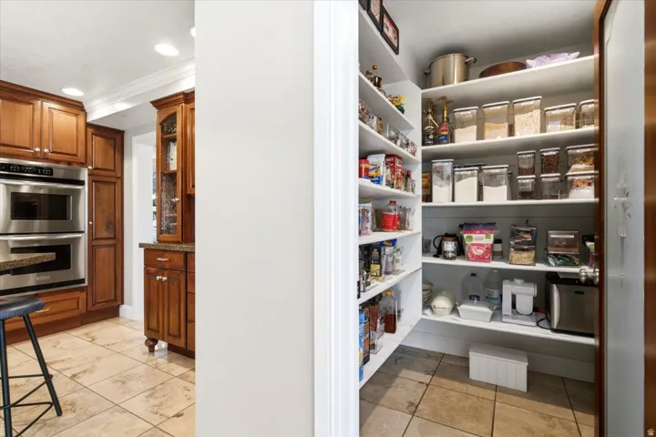 Kitchen featuring wood cabinetry, stainless steel double ovens, and stone-finish tile flooring