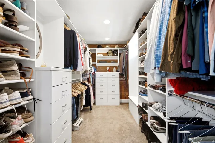 Custom closet system featuring multiple hanging rods, built-in shelving, integrated drawers, and recessed lighting