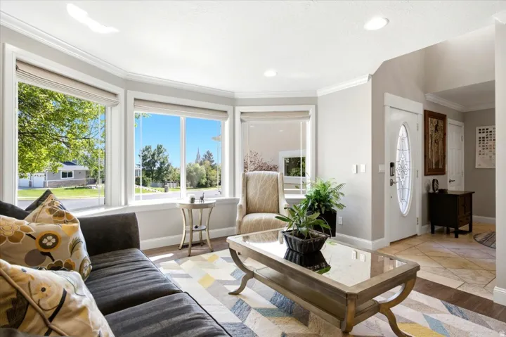 Bay window with multiple large panes, white trim, recessed lighting, crown molding, and a white front door with an oval glass insert