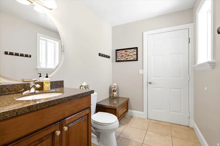 Bathroom featuring a wood-finish vanity with a built-in sink, granite countertop, and polished chrome faucet