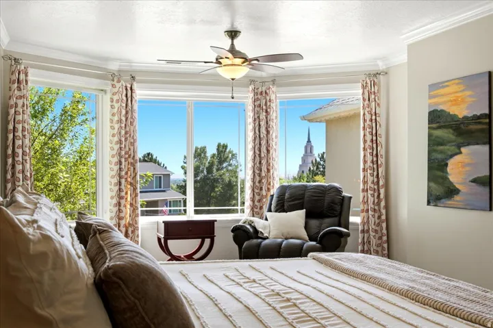Bay window featuring multiple large windows, crown molding, and a ceiling fan