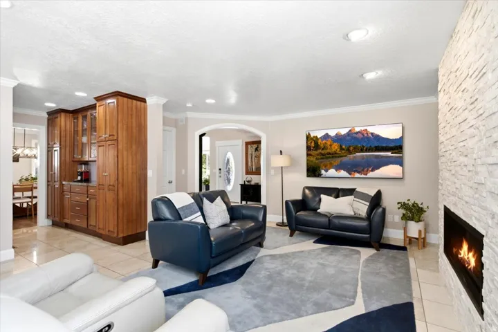 Recessed lighting illuminates the open living area featuring a stone accent wall, a built-in fireplace, and tile flooring