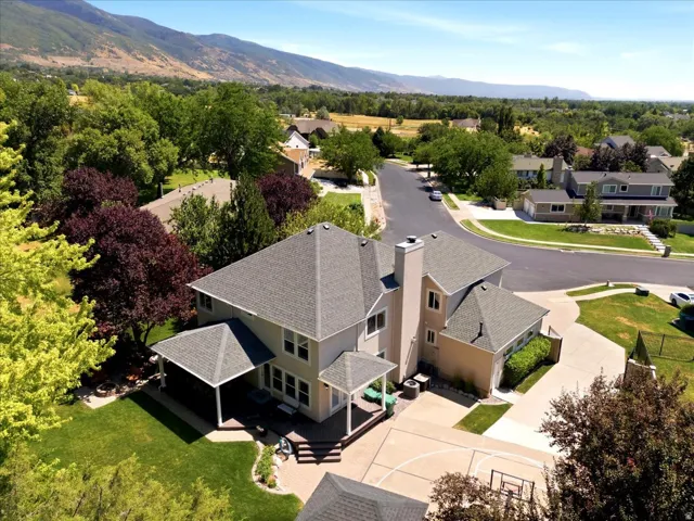 Expansive property featuring a multi-level residence with a covered patio, paved driveway, and established landscaping
