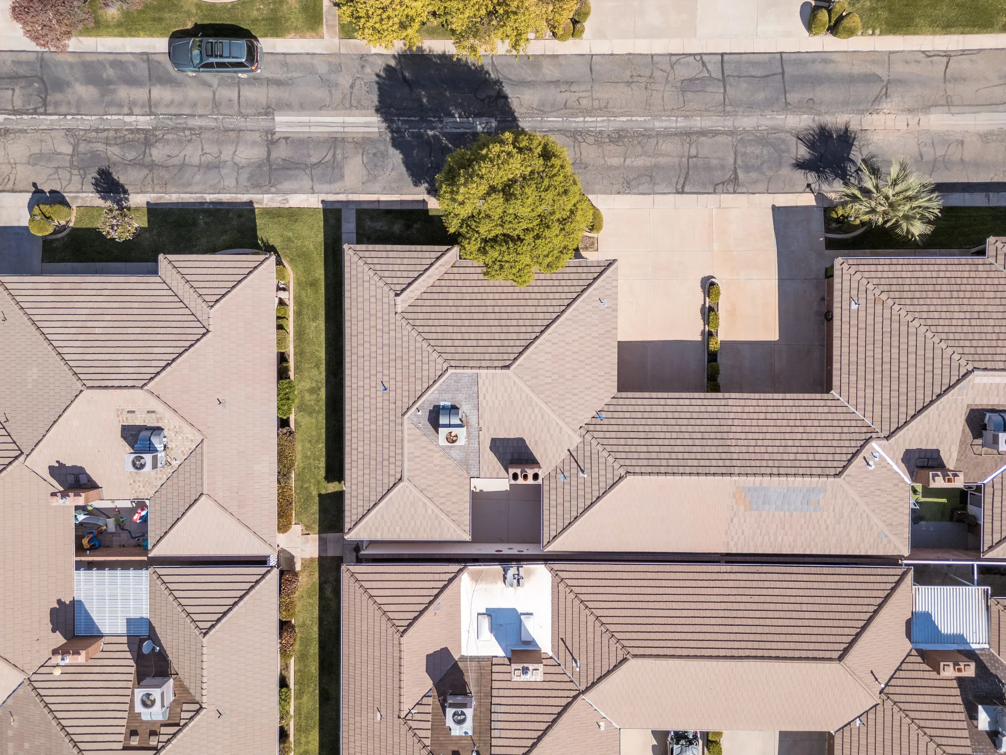 Terracotta tile roofing with multiple gables, surrounded by concrete paving and landscaped green space