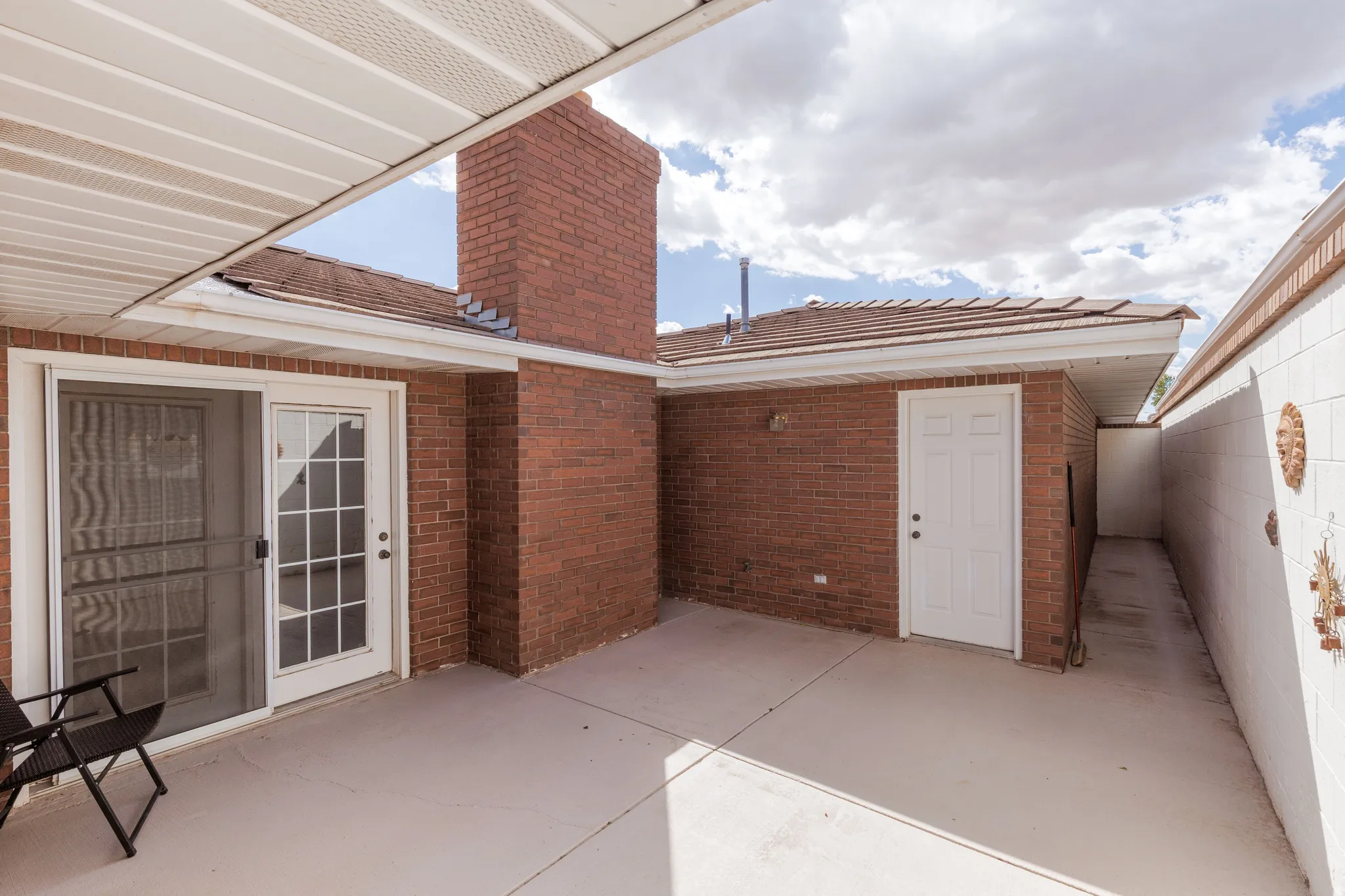 Covered patio space featuring a brick exterior and a white sliding glass door