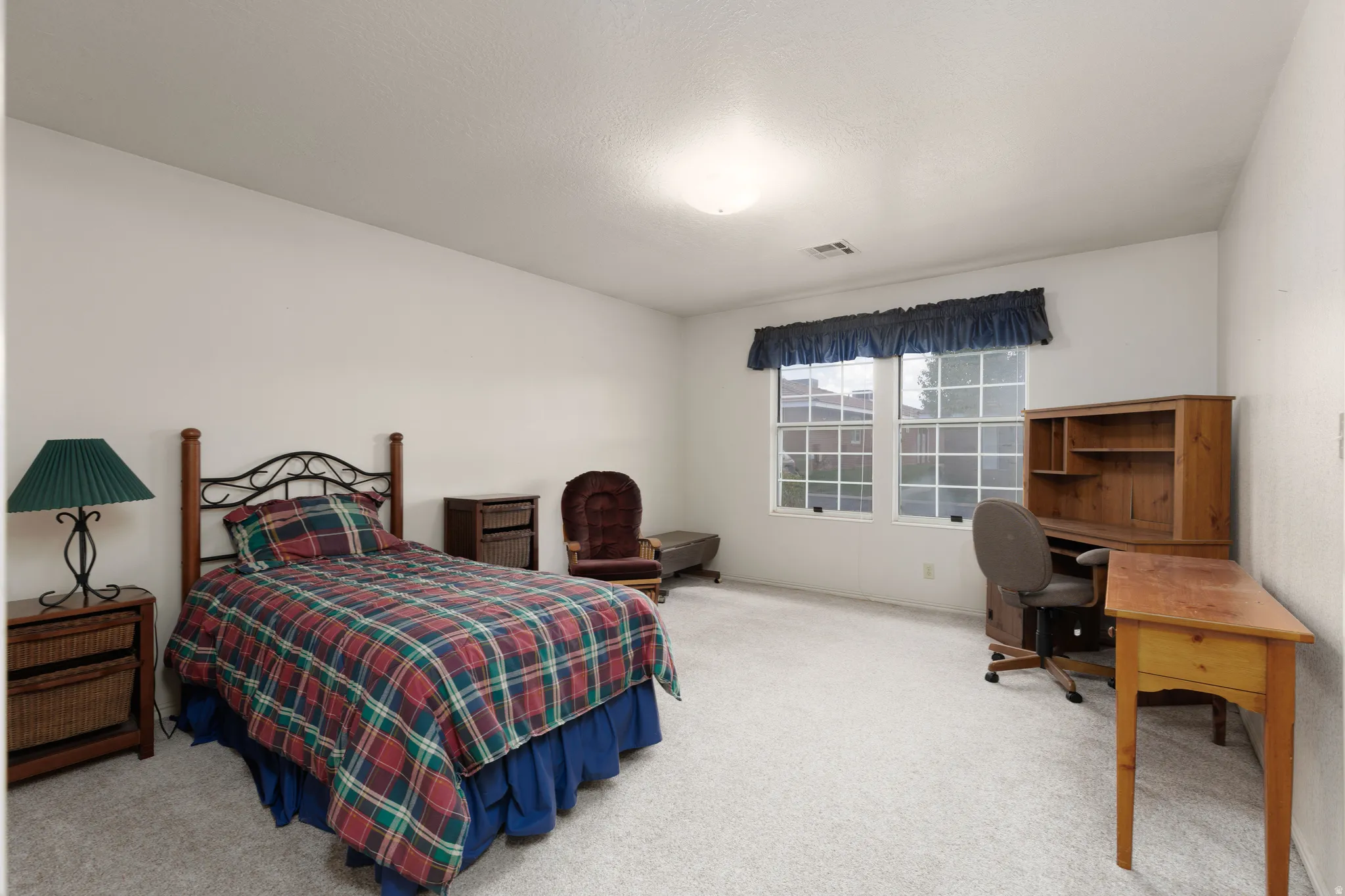 Carpeted bedroom featuring a double window with blinds and a flush mount ceiling light