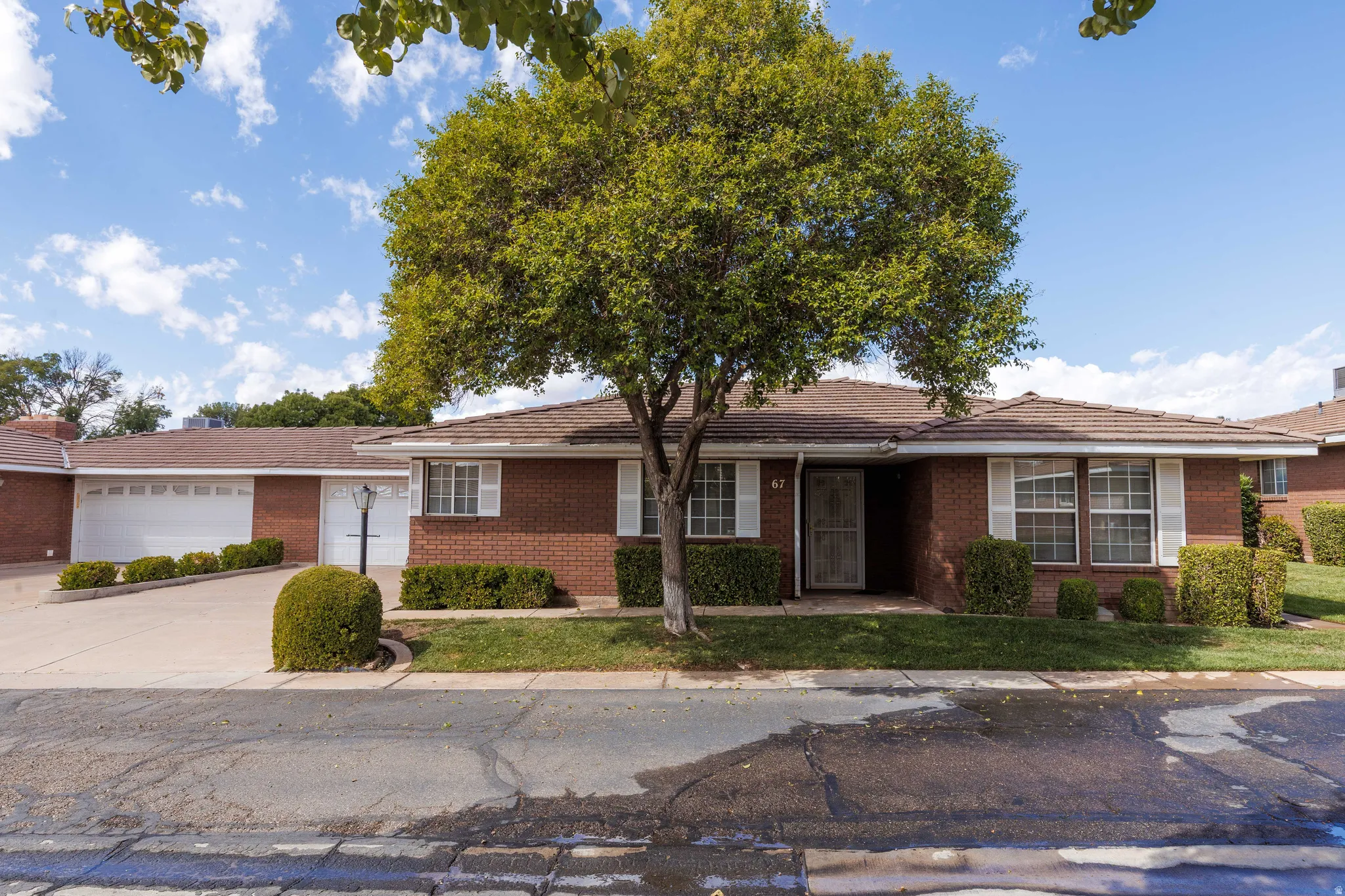 Brick exterior with a tiled roof, white window shutters, and an attached two-car garage