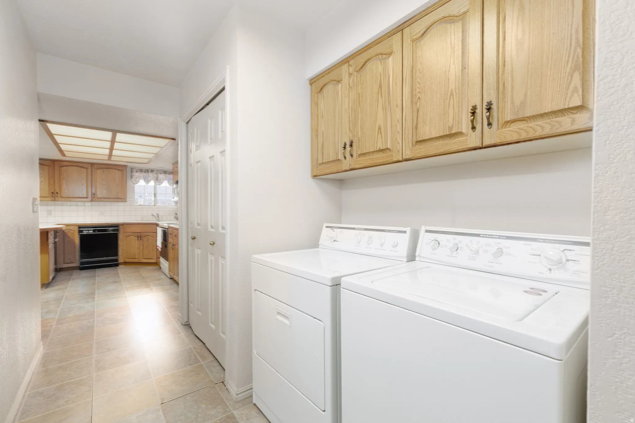 In-unit laundry appliances with overhead wood-finish cabinetry