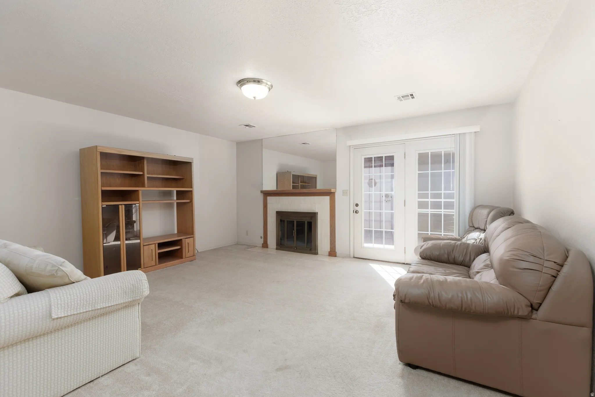 Fireplace with wood mantel, built-in entertainment center, and French doors