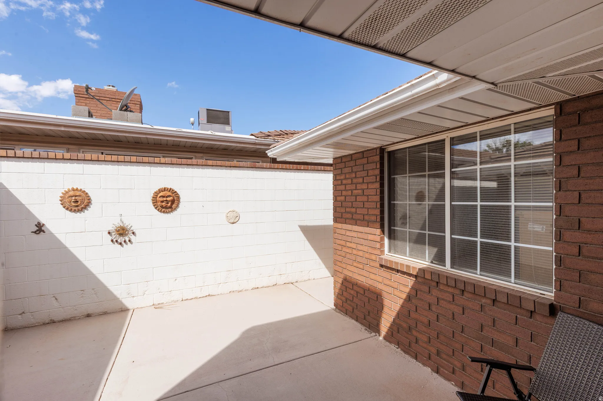 Concrete patio area enclosed by a white masonry wall
