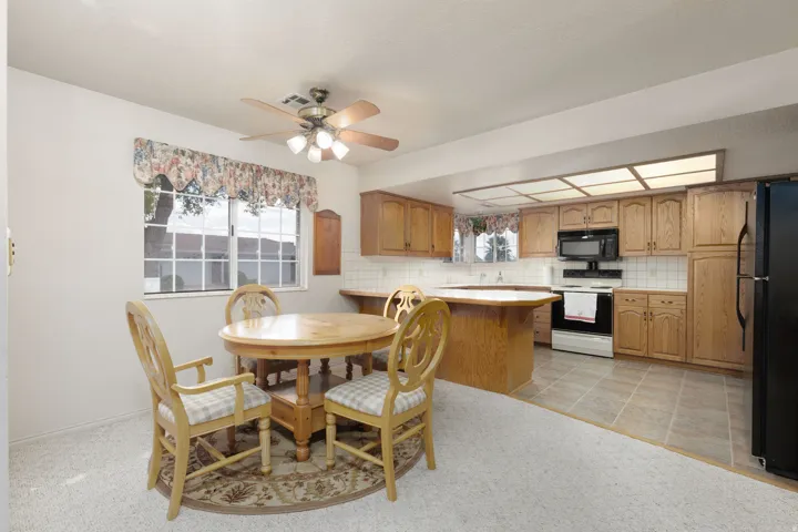 Kitchen with wood-finish cabinetry, white tile backsplash, and integrated black appliances