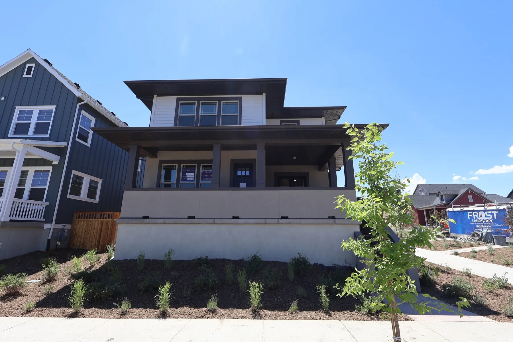 Contemporary two-story exterior with a covered porch, horizontal white siding, and a contrasting dark roofline