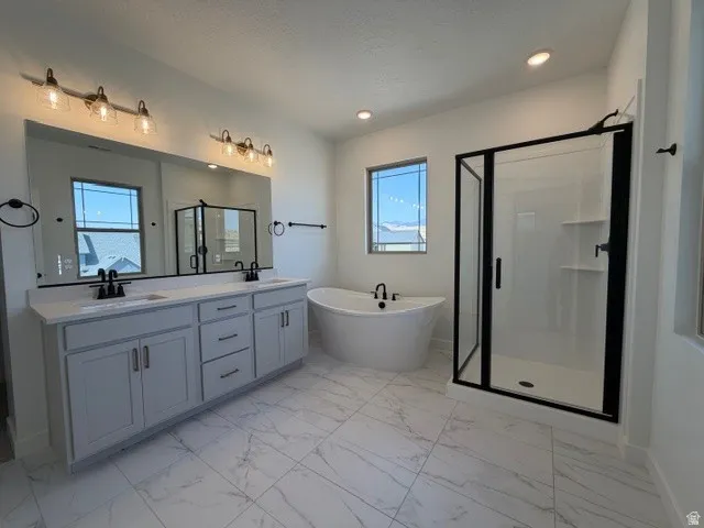 Spacious bathroom featuring a freestanding soaking tub, a walk-in shower with black-framed glass enclosure, and a double vanity with stone countertops