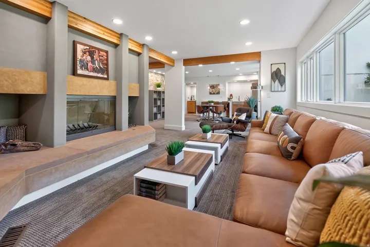 Gas fireplace with a stone hearth, exposed wood beams, recessed lighting, large windows, and a carpeted floor