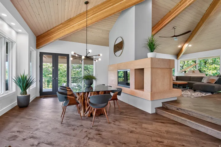 Vaulted wood-paneled ceilings with exposed beams, wood-finish flooring, and a stone-clad fireplace with a pass-through opening