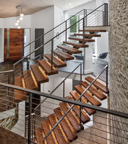 Floating solid walnut wood-finish stairs with metal cable railings