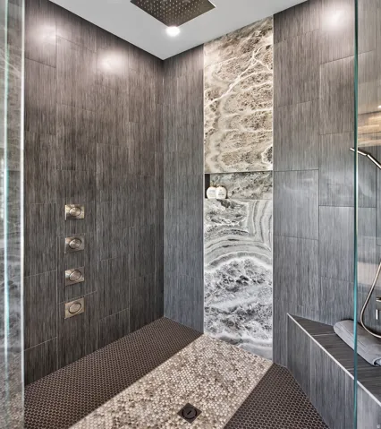 Walk-in shower with textured wall tile and a contrasting stone accent panel