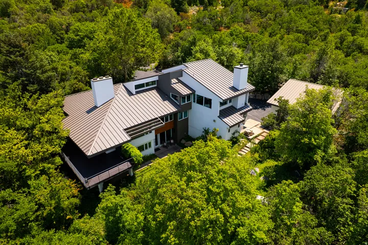 Contemporary multi-level exterior with a metal roof, multiple chimneys, and integrated large windows